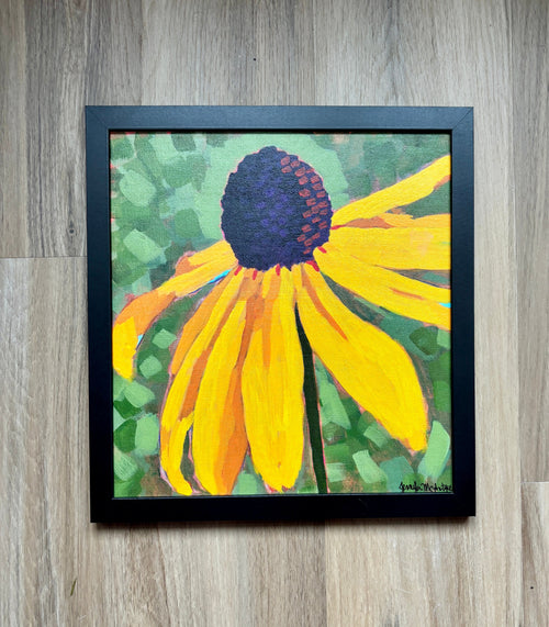 Framed painting of a yellow flower on a wooden surface