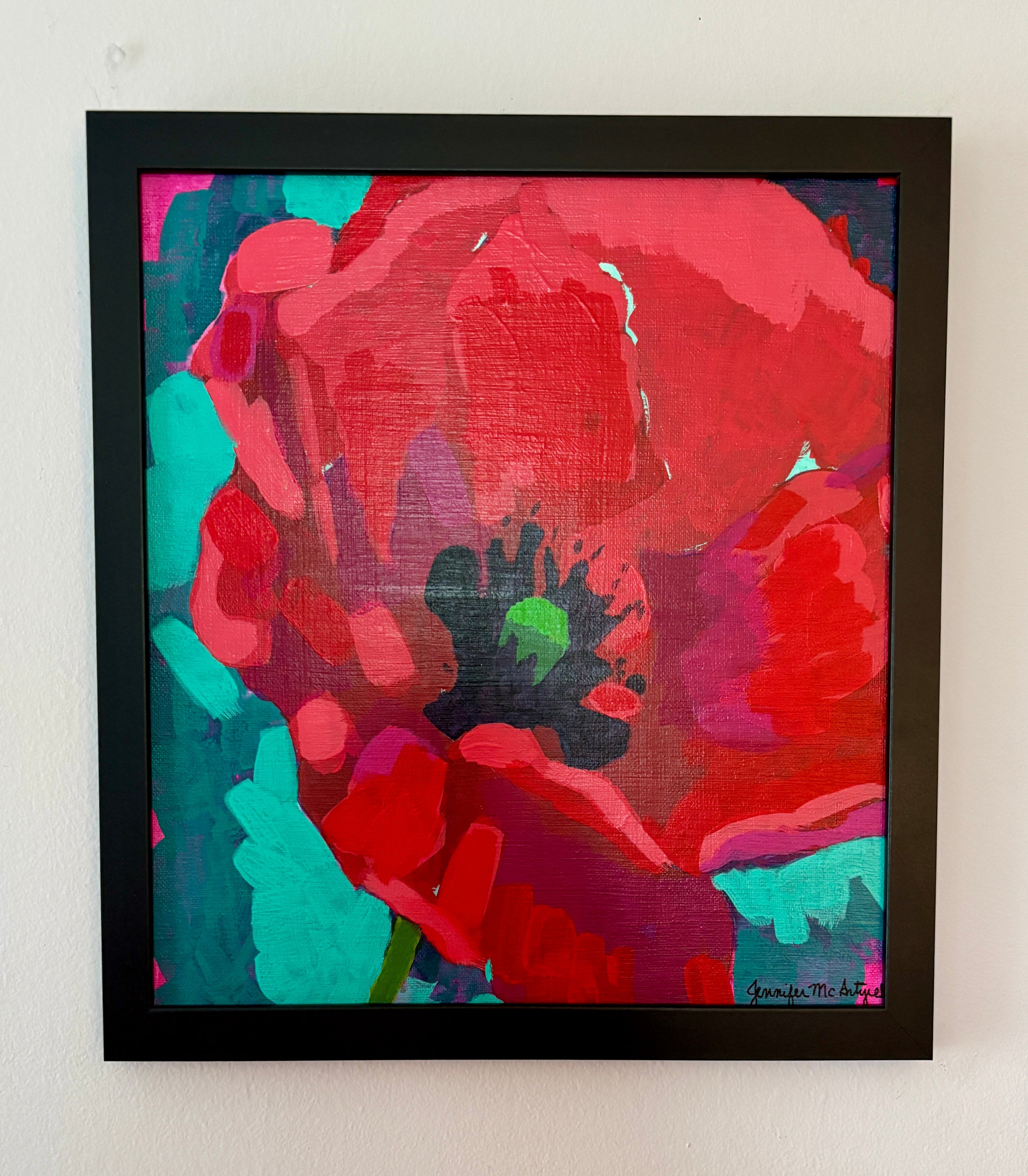 Framed abstract painting with red and green colors on a white wall