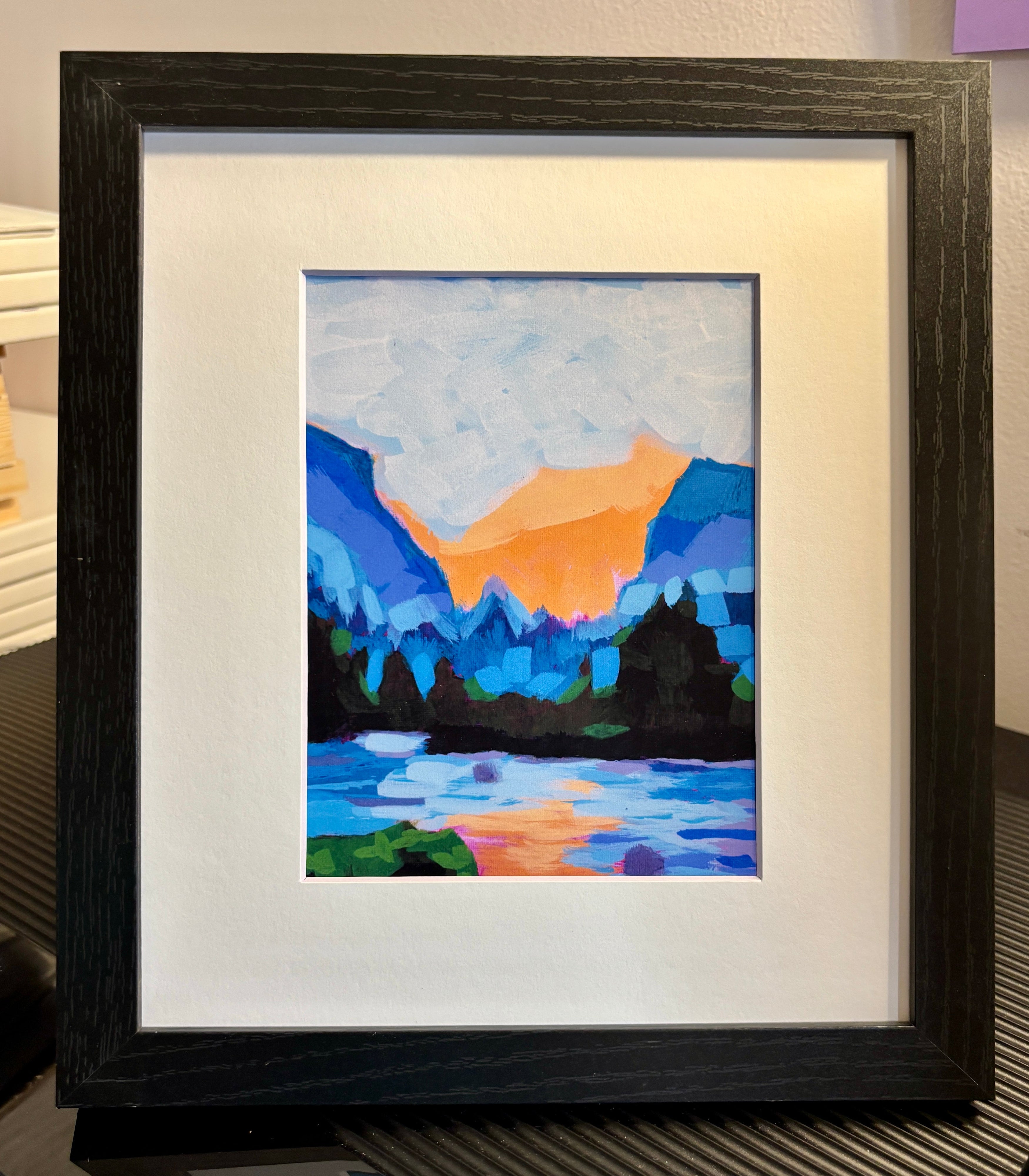 Framed abstract artwork with colorful mountain and landscape design.